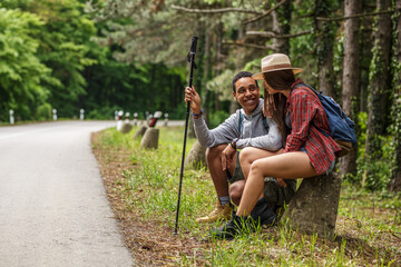 Young couple hiking in nature.They sitting and resting by the old country road.	
