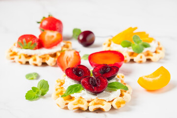 Top view of traditional Belgian waffles with soft cheese, fruits and berries with copy space.
