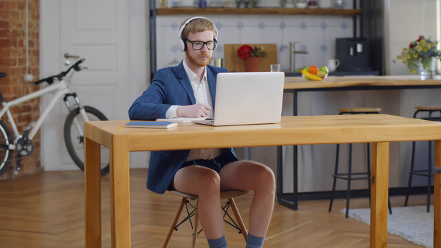 Young Freelancer Man Sitting In Home Office In Headphones And Working On Laptop