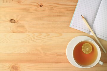 Cup of Hot Lime Tea with Lined Notebook and Pencil on Wooden Table