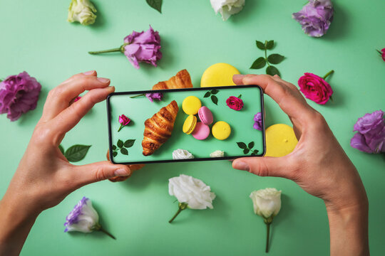 food blog - blogger taking picture of macarons and croissant with phone
