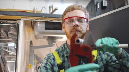 Close up of young handsome handyman assembling sink pipes