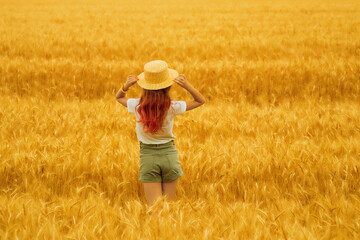 A girl walks through a wheat field on a hot day