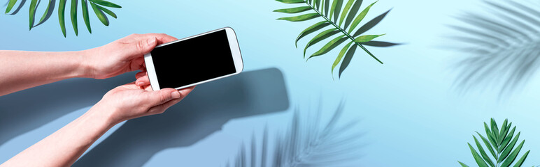 Smartphone with tropical palm leaves and shadow - flat lay