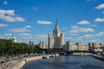 Panoramic view of the house on Kotelnicheskaya embankment and the Moscow river with pleasure boats on a clear summer day with blue sky and white clouds and copy space