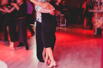 Couples dancing argentinian dance milonga in the ballroom, tango lesson in the red lights, dance festival