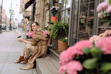 girl with a mug of coffee near flowers in the city