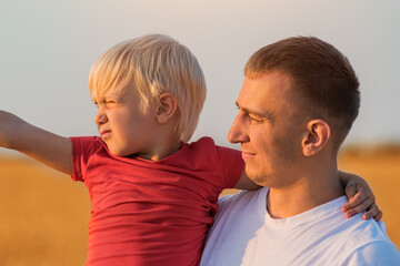 Fair haired boy and young father portrait. Countryside.