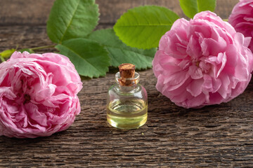 Obraz na płótnie Canvas A bottle of rose essential oil with rose de mai flowers