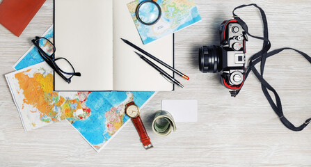 Travel plan background. Ready for the trip. Map, blank notebook, camera, glasses, pencils, clock and money on light wooden table. Top view. Flat lay.