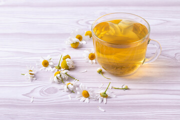 herbal fresh hot tea in a glass cup and camomile flowers