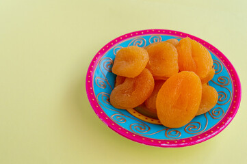 Dried apricot. Apricots in a group on a beautiful plate, yellow background pattern, space for text. Healthy fruits