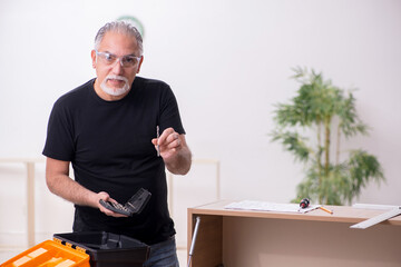 Old male carpenter working indoors