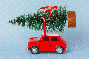 Red toy car  delivering a Christmas tree . Christmas  celebration  concept.