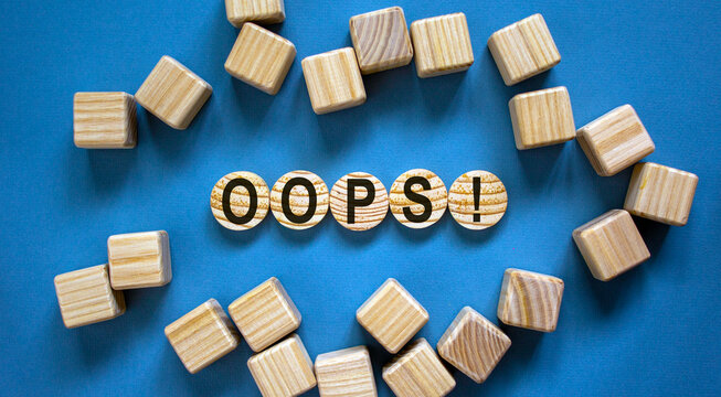Oops sign on wooden cut circles. Wooden cubes. Beautiful blue background, copy space. Concept.