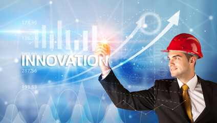 Young businessman with helmet drawing INNOVATION inscription, modern business technology concept