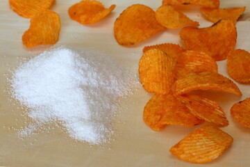Chipsy o smaku papryki obok białej soli kuchennej, jedzenie śmieciowe, zawartośc soli