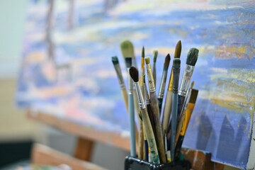 Artist's brushes on the background of a painting with an easel. Waiting for the master