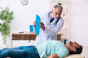 Obraz premium Injured young man visiting old doctor