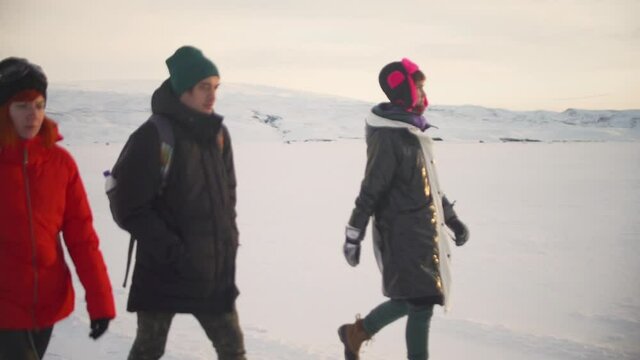 three traveler friends walking on a snow desert in Iceland at sunrise