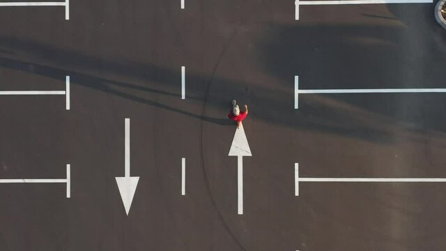 The man is walking along the empty parking lot