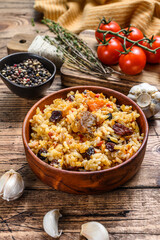 Obraz na płótnie Canvas Rice pilaf with lamb meat and vegetables in a wooden bowl. wooden background. Top view