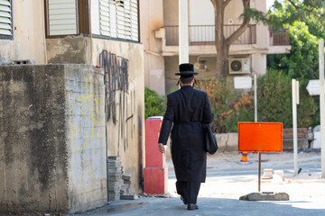jew with long black suit and hat walking down the street