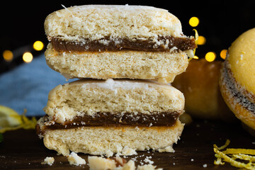 tipico alfajor cordobés de argentina y alfajor de maicena con dulce de leche con cafe al paso, limón menta medialunas  sobre madera con fondo oscuro