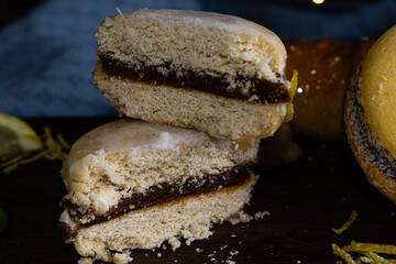 tipico alfajor cordobés de argentina y alfajor de maicena con dulce de leche con cafe al paso, limón menta medialunas  sobre madera con fondo oscuro