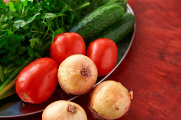 healthy food - fresh vegetables and greens on a wooden background, greens, onion and tomatoes
