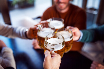 Friends clinking glasses with beer in beer pub
