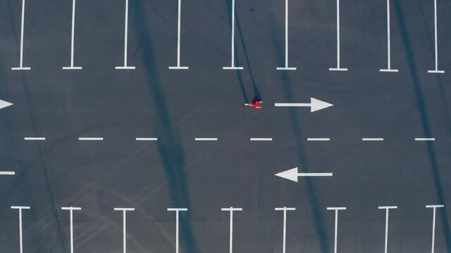 The aerial view of the guy walks along the empty parking lot
