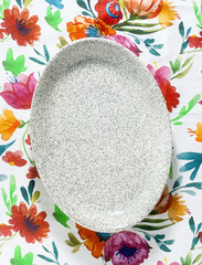 empty oval dish on a bright colorful tablecloth
