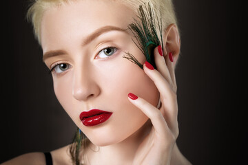 Portrait of a beautiful woman with short blonde hair, beautiful fresh make-up and with feather...