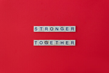 Words Stronger Together. Wooden blocks with lettering on red background. Minimal concept. Top view, layout