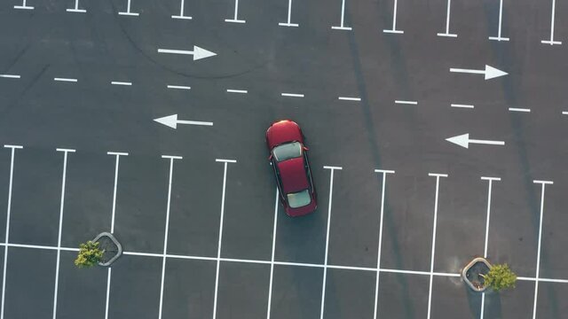 The red car leaves the empty parking lot