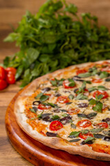 Cherry tomato pizza, black olive and basil on wooden background