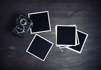 Blank photos and vintage camera on wooden background. Square photo frames template. Flat lay.