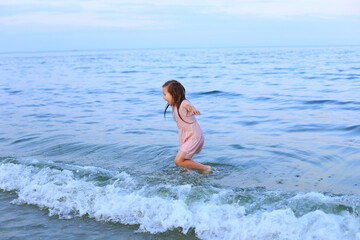 Fototapeta na wymiar A barefoot child walks by the sea
