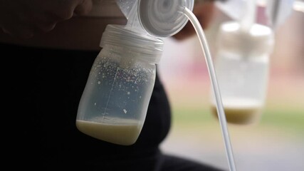 Mom use electric breast pump feeding for her baby.