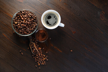 Fresh tasty coffee. Coffee cup, coffee beans and ground powder on wooden background. Top view. Flat lay.