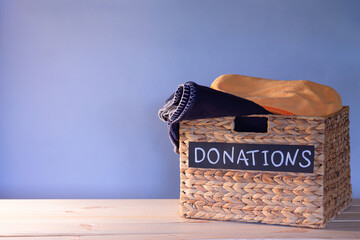 Donation box for clothing donations on a blue background. Charity and donation concept. Copy space.