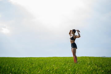 Attractive girl athlete does warm-up outdoors, exercises for muscles. Young woman go in for sports, healthy lifestyle, athletic body. She is in sportswear, black top and shorts