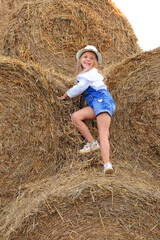 Naklejka na ściany i meble Portrait of a little girl on a haystack in summer