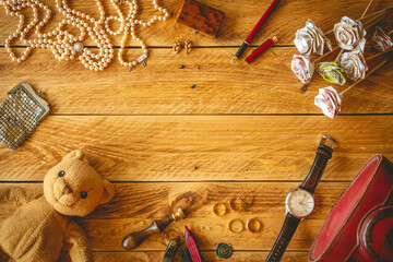 Vintage objects and jewelry in a wooden table with copy space in the middle.