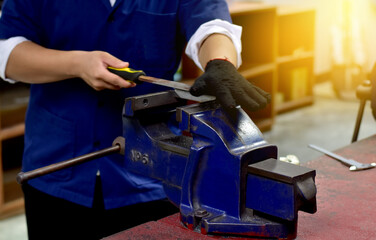 Student file a metal in workshop class . Focus on the workpiece 
