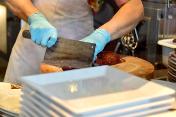 Street food merchant slicing duck meat using large knife for sale in the market during Songkran Festival of Thailand.