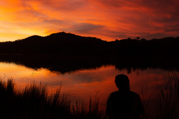 Fototapeta na wymiar Orange skies reflecting on lake showing a man in silhouette