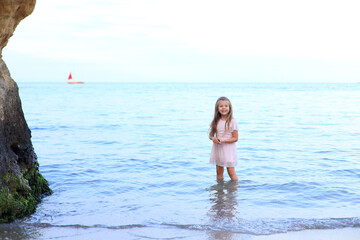 Cute girl stands on the seashore in summer