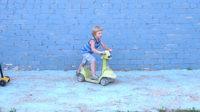 Funny blond boys ride scooters and toy car on gray background. Children imitate collisions, traffic violations and car accident. Teens Learn to Drive Safely
